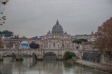Tiber Nehri üzerinde tarihi bir şehir. Akşamları ünlü Ponte Sant 'Angelo köprüsü. Gün batımında yağmurlu hava ve Basilica di San Pietro, Roma, İtalya manzarası