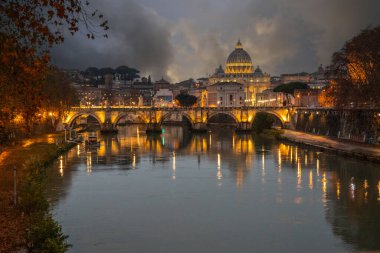 Tiber Nehri üzerinde tarihi bir şehir. Akşamları ünlü Ponte Sant 'Angelo köprüsü. Gün batımında yağmurlu hava ve Basilica di San Pietro, Roma, İtalya manzarası