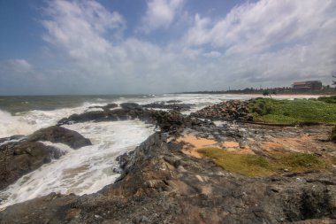 Plaj, lav kayaları ve bitki örtüsüyle akşam vakti deniz manzarası. Indurwa, Bentota Sahili, Sri Lanka, Hindistan, Asya 'da bulutlu manzara