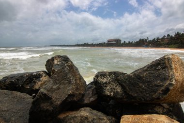 Beach, with lava rocks and vegetation, view of the sea in the evening at sunset. Landscape with clouds in Induruwa, Bentota Beach, Sri Lanka, India, Asia clipart