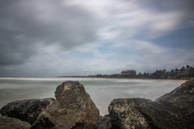 Beach, with lava rocks and vegetation, view of the sea in the evening at sunset. Landscape with clouds in Induruwa, Bentota Beach, Sri Lanka, India, Asia clipart