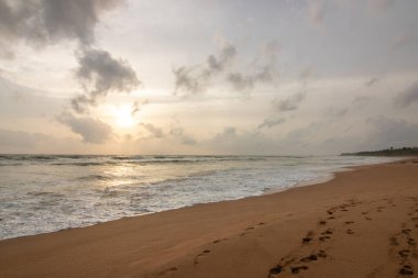 Deniz manzarası var. Ufukta deniz manzaralı uzun ve ıssız bir sahil. Kumda bir fırtınanın dalgaları kopar ve gün batımında resme özel bir dokunuş verir. Bentota, Sri Lanka, Asya