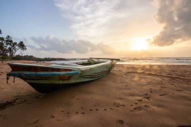 Deniz manzarası var. Ufukta deniz manzaralı uzun ve ıssız bir sahil. Kumda bir fırtınanın dalgaları kopar ve gün batımında resme özel bir dokunuş verir. Bentota, Sri Lanka, Asya