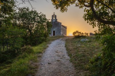 Önünde bir patika olan küçük tarihi bir kilise. Kilise, gündoğumunda ve Akdeniz manzarasında bir uçurumun üzerinde duruyor. Hırvatistan 'ın Istria kentinin tarihi Bresc köyü