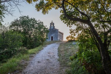 Önünde bir patika olan küçük tarihi bir kilise. Kilise, gündoğumunda ve Akdeniz manzarasında bir uçurumun üzerinde duruyor. Hırvatistan 'ın Istria kentinin tarihi Bresc köyü