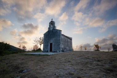 Önünde bir patika olan küçük tarihi bir kilise. Kilise, gündoğumunda ve Akdeniz manzarasında bir uçurumun üzerinde duruyor. Hırvatistan 'ın Istria kentinin tarihi Bresc köyü