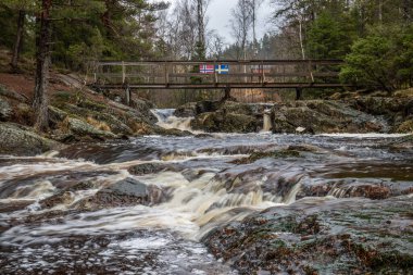 Landscape shot of a large waterfall in the forest and nature. Autumn landscape The Elgafossen Vattenfall river provides a natural border between Sweden and Norway at Vassbotten, Scandinavia clipart