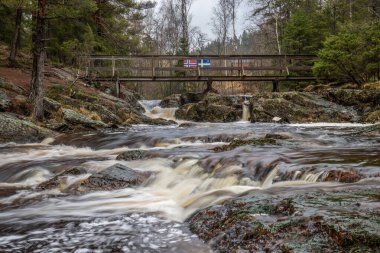 Landscape shot of a large waterfall in the forest and nature. Autumn landscape The Elgafossen Vattenfall river provides a natural border between Sweden and Norway at Vassbotten, Scandinavia clipart