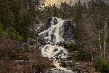 Landscape shot of a large waterfall in the forest and nature. Autumn landscape The Elgafossen Vattenfall river provides a natural border between Sweden and Norway at Vassbotten, Scandinavia clipart