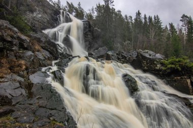 Landscape shot of a large waterfall in the forest and nature. Autumn landscape The Elgafossen Vattenfall river provides a natural border between Sweden and Norway at Vassbotten, Scandinavia clipart