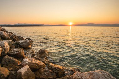 Sahil, gün batımını gören bir liman. Hırvatistan 'ın Krk kentinde deniz manzarası