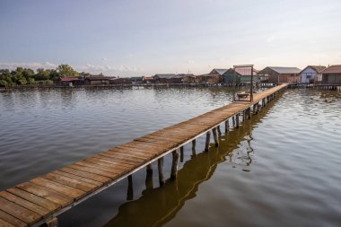 Wooden houses in the water. Holiday resort in the lake at sunset. Long wooden walkways lead to the individual houses. Landscape photo of the floating village of Bokodi, Lake Balaton, Hungary clipart