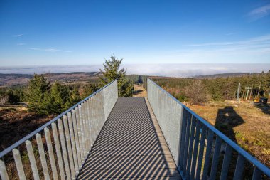 Çelik yolu ve bakış açısı olan ahşap heykel. Dağ manzarası, vadide mavi gökyüzü sisi. Erbeskopf rüzgar ses heykelinde sabah, Hilscheid, Rhineland-Palatinate, Almanya