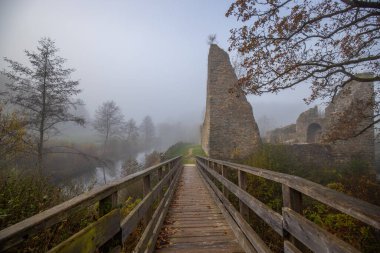 Ruins of a castle. Landscape shot in autumn. Defensive structure in a lake. Misty landscape in the morning at the historical sight in Morbach, Baldenau castle ruins, Rhineland-Palatinate, Germany clipart