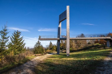 Wooden sculpture with a steel walkway and viewpoint. Landscape shot on a mountain, blue sky fog in the valley. Morning at the Erbeskopf wind sound sculpture, Hilscheid, Rhineland-Palatinate, Germany clipart