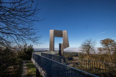 Çelik yolu ve bakış açısı olan ahşap heykel. Dağ manzarası, vadide mavi gökyüzü sisi. Erbeskopf rüzgar ses heykelinde sabah, Hilscheid, Rhineland-Palatinate, Almanya