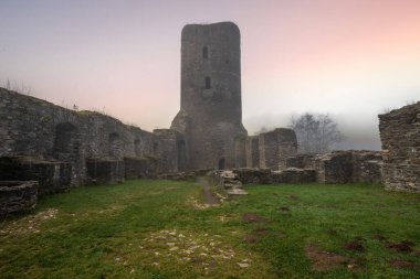 Ruins of a castle. Landscape shot in autumn. Defensive structure in a lake. Misty landscape in the morning at the historical sight in Morbach, Baldenau castle ruins, Rhineland-Palatinate, Germany clipart