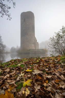 Ruins of a castle. Landscape shot in autumn. Defensive structure in a lake. Misty landscape in the morning at the historical sight in Morbach, Baldenau castle ruins, Rhineland-Palatinate, Germany clipart