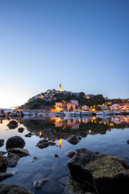 Liman ve sahil, tepenin üstünde eski bir köy. Gemiler suya yansıyor, güneş Adriyatik 'in ufuklarından doğuyor. Vrbnik, Krk, Hırvatistan 'dan güzel manzara görüntüleri