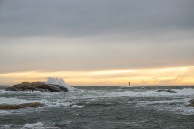 Fırtınada bir deniz feneri duruyor. Uzun vadede vahşi deniz. Kuzey Denizi 'nde birçok kayanın olduğu bir sahilde gün batımı. İsveç, İskandinavya, Avrupa 'da deniz manzarası