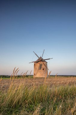 Manzarada ahşap kanatları olan yel değirmeni. Tarlalar, çayırlar ve çiçekler gün batımında belirir. Doğada bir değirmenle çekilmiş manzara. Macaristan 'daki Balaton bölgesi için tarihsel olarak alışılmadık bir durum.