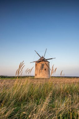 Manzarada ahşap kanatları olan yel değirmeni. Tarlalar, çayırlar ve çiçekler gün batımında belirir. Doğada bir değirmenle çekilmiş manzara. Macaristan 'daki Balaton bölgesi için tarihsel olarak alışılmadık bir durum.