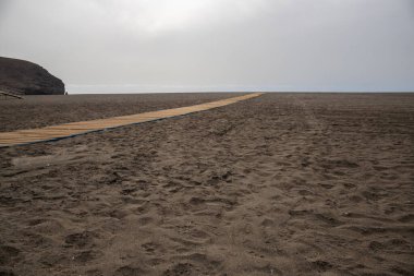 Deniz manzarası var. Küçük bir kasabanın limanındaki şehir plajı. Kumsal ve sahil Gran Tarajal, Las Palmas, Fuerteventura, İspanya