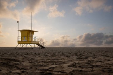 Deniz manzarası var. Siyah lav plajında sarı cankurtaran kulübeleri olan şehir plajı. Gran Tarajal, Las Palmas, Fuerteventura, İspanya 'da kumlu havuz