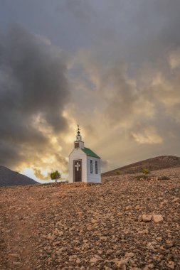 Verimsiz volkanik bir arazide küçük, beyaz ahşap bir şapel. Gündoğumu, İspanya 'nın Kanarya Adaları' ndaki Fuerteventura Adası 'ndaki Ermita Protestante de Violante kilisesinin manzara görüntüsü.