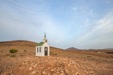 Verimsiz volkanik bir arazide küçük, beyaz ahşap bir şapel. Gündoğumu, İspanya 'nın Kanarya Adaları' ndaki Fuerteventura Adası 'ndaki Ermita Protestante de Violante kilisesinin manzara görüntüsü.