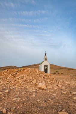 Verimsiz volkanik bir arazide küçük, beyaz ahşap bir şapel. Gündoğumu, İspanya 'nın Kanarya Adaları' ndaki Fuerteventura Adası 'ndaki Ermita Protestante de Violante kilisesinin manzara görüntüsü.