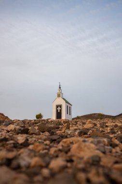 small cute white wooden chapel in a barren volcanic landscape. Sunrise, landscape shot of Ermita Protestante de Violante church, on Fuerteventura island, Canary Islands, Spain clipart