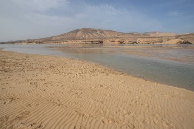 Deniz kenarında sığ bir gölü olan kumlu bir sahil. Akşamları verimsiz manzara çekimleri. Playa de Sotavento de Janda, Fuerteventura, Kanarya Adaları, İspanya