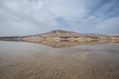 Deniz kenarında sığ bir gölü olan kumlu bir sahil. Akşamları verimsiz manzara çekimleri. Playa de Sotavento de Janda, Fuerteventura, Kanarya Adaları, İspanya