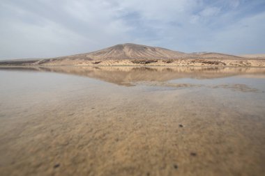 Deniz kenarında sığ bir gölü olan kumlu bir sahil. Akşamları verimsiz manzara çekimleri. Playa de Sotavento de Janda, Fuerteventura, Kanarya Adaları, İspanya