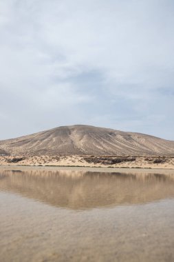 Deniz kenarında sığ bir gölü olan kumlu bir sahil. Akşamları verimsiz manzara çekimleri. Playa de Sotavento de Janda, Fuerteventura, Kanarya Adaları, İspanya