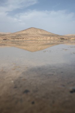 Deniz kenarında sığ bir gölü olan kumlu bir sahil. Akşamları verimsiz manzara çekimleri. Playa de Sotavento de Janda, Fuerteventura, Kanarya Adaları, İspanya