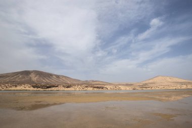 Deniz kenarında sığ bir gölü olan kumlu bir sahil. Akşamları verimsiz manzara çekimleri. Playa de Sotavento de Janda, Fuerteventura, Kanarya Adaları, İspanya