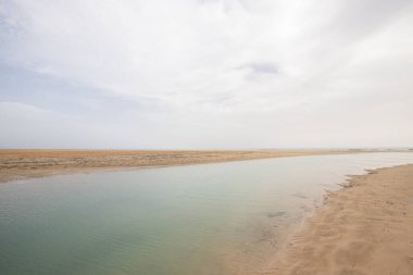 Deniz kenarında sığ bir gölü olan kumlu bir sahil. Akşamları verimsiz manzara çekimleri. Playa de Sotavento de Janda, Fuerteventura, Kanarya Adaları, İspanya