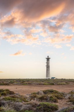 Doğa koruma alanında deniz feneriyle çekilen alacakaranlık manzarası. Gün batımında deniz manzarası. Hafif bir Kalima sırasında deniz feneri, Morro Jable 'da kum fırtınası, Fuerteventura, Kanarya Adaları, İspanya