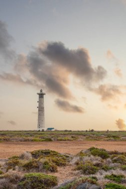 Doğa koruma alanında deniz feneriyle çekilen alacakaranlık manzarası. Gün batımında deniz manzarası. Hafif bir Kalima sırasında deniz feneri, Morro Jable 'da kum fırtınası, Fuerteventura, Kanarya Adaları, İspanya