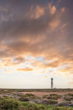Doğa koruma alanında deniz feneriyle çekilen alacakaranlık manzarası. Gün batımında deniz manzarası. Hafif bir Kalima sırasında deniz feneri, Morro Jable 'da kum fırtınası, Fuerteventura, Kanarya Adaları, İspanya