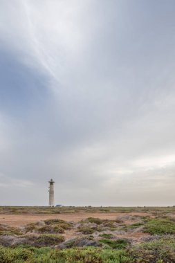 Doğa koruma alanında deniz feneriyle çekilen alacakaranlık manzarası. Gün batımında deniz manzarası. Hafif bir Kalima sırasında deniz feneri, Morro Jable 'da kum fırtınası, Fuerteventura, Kanarya Adaları, İspanya