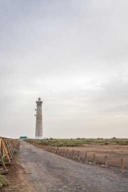 Doğa koruma alanında deniz feneriyle çekilen alacakaranlık manzarası. Gün batımında deniz manzarası. Hafif bir Kalima sırasında deniz feneri, Morro Jable 'da kum fırtınası, Fuerteventura, Kanarya Adaları, İspanya