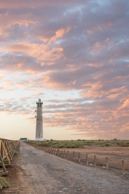 Doğa koruma alanında deniz feneriyle çekilen alacakaranlık manzarası. Gün batımında deniz manzarası. Hafif bir Kalima sırasında deniz feneri, Morro Jable 'da kum fırtınası, Fuerteventura, Kanarya Adaları, İspanya