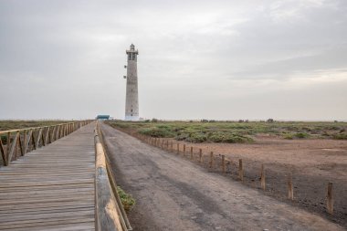 Doğa koruma alanında deniz feneriyle çekilen alacakaranlık manzarası. Gün batımında deniz manzarası. Hafif bir Kalima sırasında deniz feneri, Morro Jable 'da kum fırtınası, Fuerteventura, Kanarya Adaları, İspanya