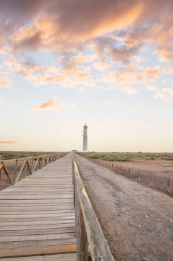 Doğa koruma alanında deniz feneriyle çekilen alacakaranlık manzarası. Gün batımında deniz manzarası. Hafif bir Kalima sırasında deniz feneri, Morro Jable 'da kum fırtınası, Fuerteventura, Kanarya Adaları, İspanya