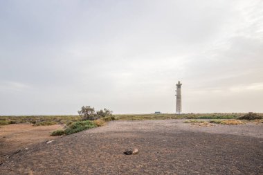 Doğa koruma alanında deniz feneriyle çekilen alacakaranlık manzarası. Gün batımında deniz manzarası. Hafif bir Kalima sırasında deniz feneri, Morro Jable 'da kum fırtınası, Fuerteventura, Kanarya Adaları, İspanya