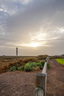 Doğa koruma alanında deniz feneriyle çekilen alacakaranlık manzarası. Gün batımında deniz manzarası. Hafif bir Kalima sırasında deniz feneri, Morro Jable 'da kum fırtınası, Fuerteventura, Kanarya Adaları, İspanya