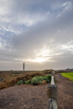 Doğa koruma alanında deniz feneriyle çekilen alacakaranlık manzarası. Gün batımında deniz manzarası. Hafif bir Kalima sırasında deniz feneri, Morro Jable 'da kum fırtınası, Fuerteventura, Kanarya Adaları, İspanya